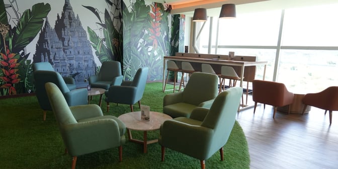 The Concordia Lounge at Yogyakarta International Airport features comfortable seating areas with armchairs and a high table, set against a mural backdrop.
