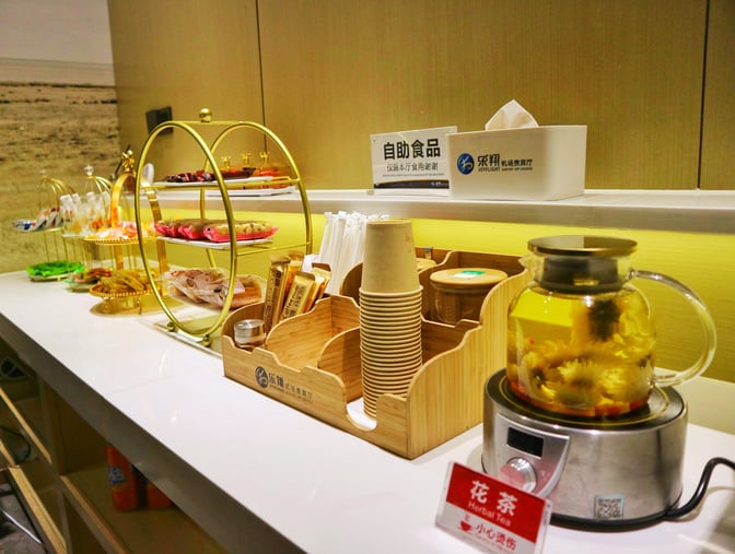 The self-serve snack station at Zhangjiajie Hehua Airport's First Class Lounge offers pastries, packaged snacks, and herbal tea.