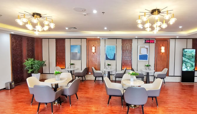 The seating area in No. 5 First Class Lounge at Zhangjiajie Hehua Airport features round tables and cushioned chairs for passenger comfort.