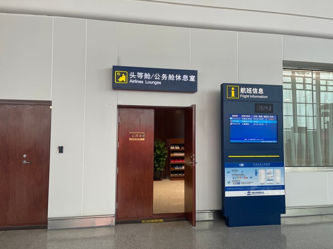 The entrance to the Airlines Lounge at Zhangjiakou Ningyuan Airport is located near a flight information display.